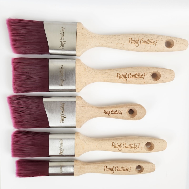 Pu&ograve; includere: Cinque pennelli angolari con setole bordeaux e ferrule argentate. I manici in legno sono etichettati "Paint Couture".