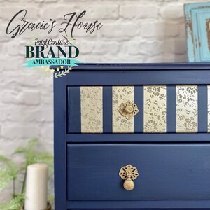 May include: A navy blue dresser with gold striped drawers and gold knobs. The dresser is decorated with the text "Gracie's House Paint Couture BRAND AMBASSADOR".