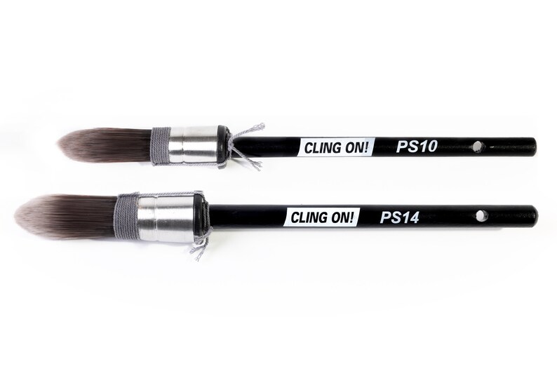 May include: Two black paint brushes with white lettering that says "CLING ON!" and "PS10" or "PS14".