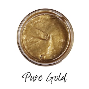 May include: A jar filled with a shimmering, golden substance. The product is labeled "Pure Gold" in elegant script. The contents appear smooth and reflective, suggesting a metallic or cosmetic product.