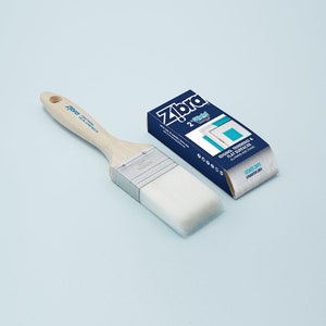 May include: A 2-inch angled paint brush with a white bristle head and a wooden handle. The brush is labeled "Zebra" and is packaged in a blue box with the text "Edging, Trimming & Flat Surfaces" and "Fewer Dips, Straighter Lines".