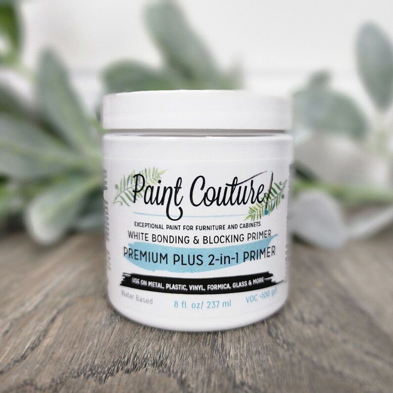 May include: White Paint Couture Premium Plus 2-in-1 Primer in a white jar with a black label. The label says "Exceptional paint for furniture and cabinets. White Bonding & Blocking Primer. Premium Plus 2-in-1 Primer. Use on metal, plastic, vinyl, formica, glass & more. Water Based. 8 fl. oz/ 237 ml. VOC 100 g/l."