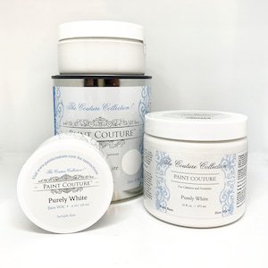 May include: Two containers of white paint, one is a sample size and the other is a full size. Both containers are labelled "Paint Couture" and "Purely White". The full size container is 16 fl oz / 473 ml. Both containers are labelled "Zero VOC".
