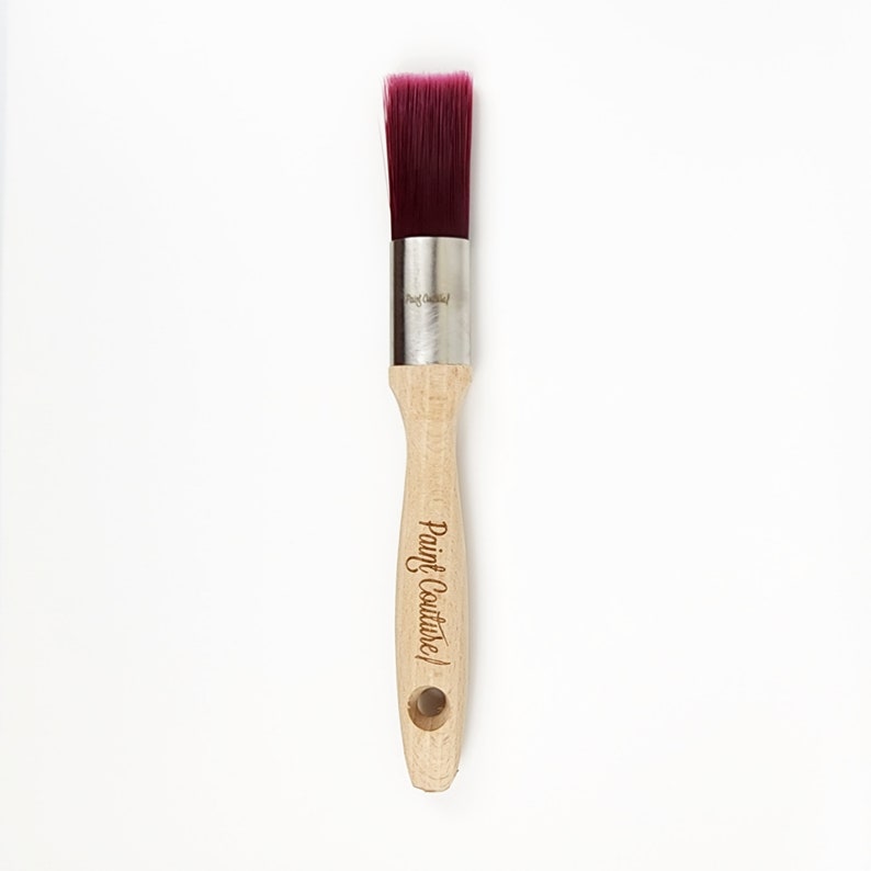Pu&ograve; includere: Un pennello per dipingere con un manico in legno. Il manico &egrave; inciso con le parole "Paint Couture!" Il pennello ha una testa di setole viola.
