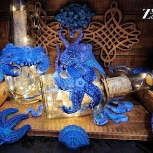 May include: A collection of blue glass bottles with a variety of sea-themed decorations, including an octopus, starfish, and seashells. The bottles are lit from within, creating a warm glow. The bottles are arranged on a wooden surface.