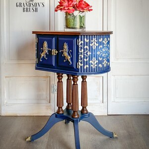 May include: A blue and brown side table with gold lion accents and a white and gold patterned design. The table has a rounded top and four legs. The table is decorated with a vase of red roses.