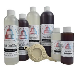 May include: A collection of Capital Crafts Paint Couture rapid casting resin bottles in various sizes and colors, including ivory and dark brown. A decorative ivory-colored casting is also present. The bottles have white caps and labels with a Capitol building design.