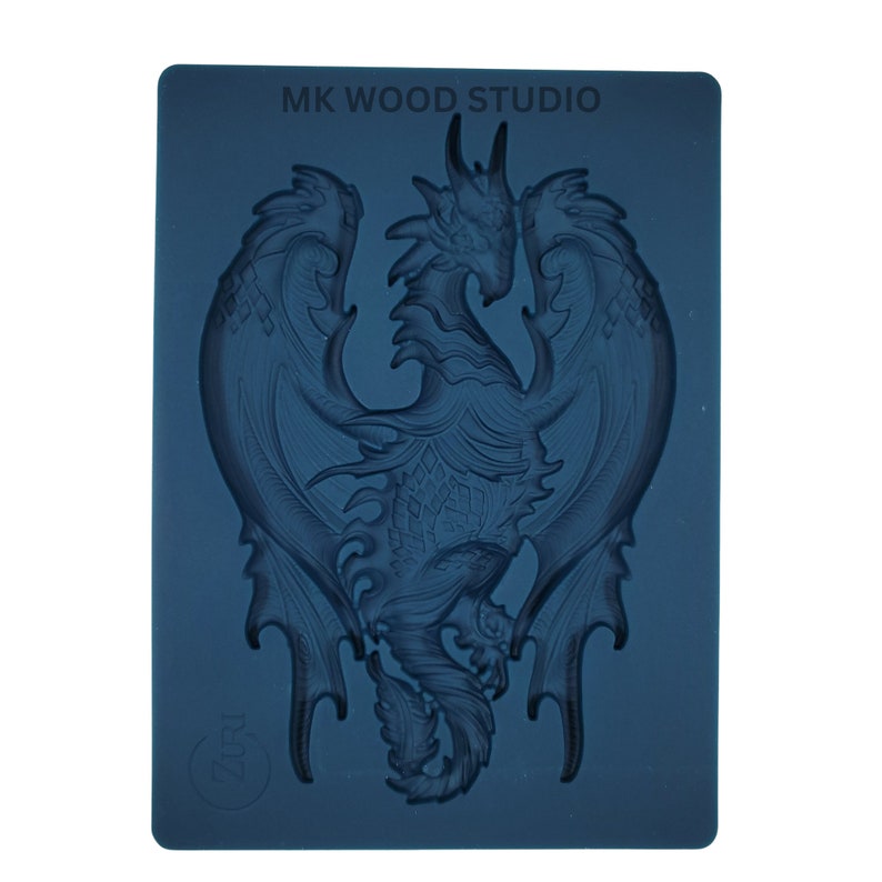 May include: A dark blue silicone mold featuring a detailed dragon design with outstretched wings. The mold has the text "MK WOOD STUDIO" at the top and a circular logo with the text "Zari" at the bottom. The dragon is the central focus.
