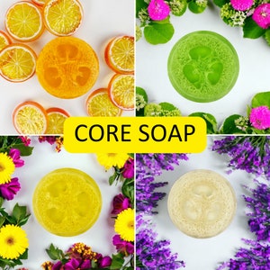 May include: Four natural loofah soap bars with different colors and textures. The soaps are arranged on a white background with flowers and greenery around them. The text "CORE SOAP" is displayed in yellow letters on a black background.