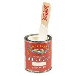 May include: A can of General Finishes Milk Paint in the color Alabaster. The paint is water-based and is shown with a wooden stir stick.