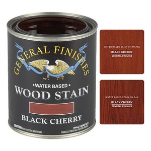 May include: A can of General Finishes water-based wood stain in the color Black Cherry. The can is black with a gold eagle logo and the text "General Finishes" and "Wood Stain" in white. The can also shows a sample of the stain color.
