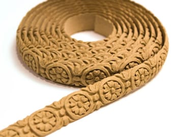 May include: A roll of decorative trim with a floral pattern. The trim is made of a light brown material and has a raised design.