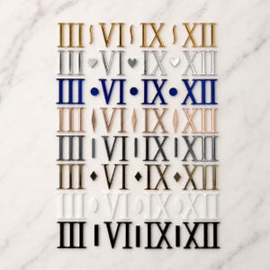 May include: A collection of Roman numeral numbers in various colors, including gold, silver, blue, and black. The numbers are arranged in rows and columns on a white marble surface. The numerals are III, VI, IX, and XII.