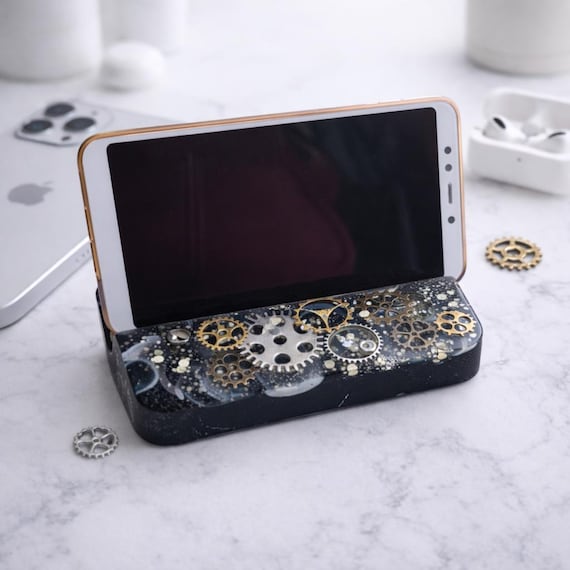 A phone stand cast with real embedded metal gears in resin — steampunk industrial art that actually holds your phone upright on your desk.