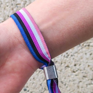 May include: A blue, pink, white and black striped wristband with a silver clasp.