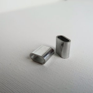 Op de afbeelding: Twee zilveren metalen kabelklemmen, een ligt op zijn zijde en de andere staat rechtop.