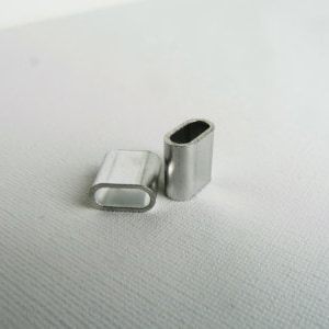 Op de afbeelding: Twee zilveren metalen krimphulzen voor het bevestigen van draadkabel of kabel. De hulzen zijn ovaalvormig en hebben een gladde, gepolijste afwerking.