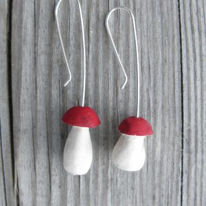 May include: A pair of silver dangle earrings with red and white mushroom charms.