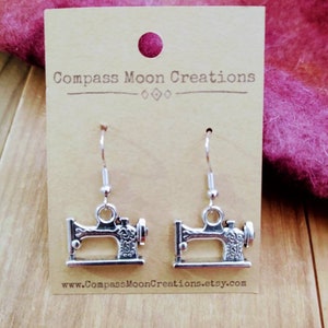 May include: Silver sewing machine earrings on a brown card with the text "Compass Moon Creations" and "www.CompassMoonCreations.etsy.com".