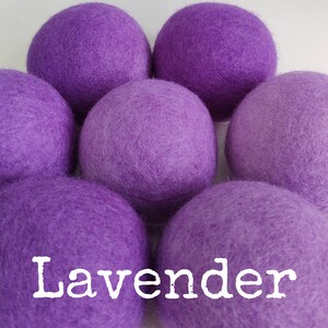 May include: Six lavender-colored wool dryer balls. The balls are soft and fluffy, and they are arranged in a circle. The word "Lavender" is written in white letters on the bottom of the image.