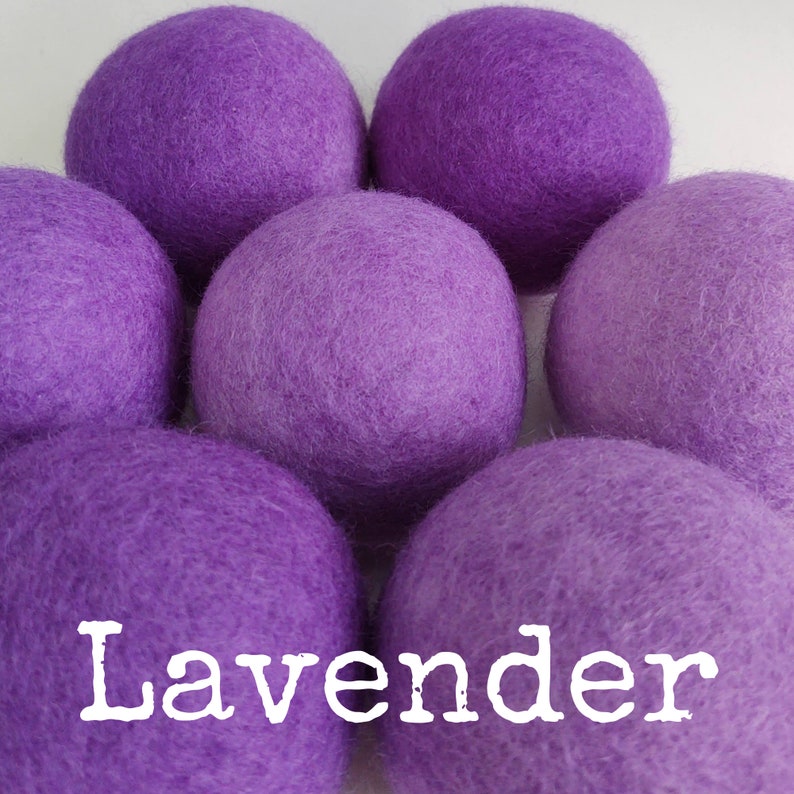 May include: Six lavender-colored wool dryer balls. The balls are soft and fluffy, and they are arranged in a circle. The word "Lavender" is written in white letters on the bottom of the image.