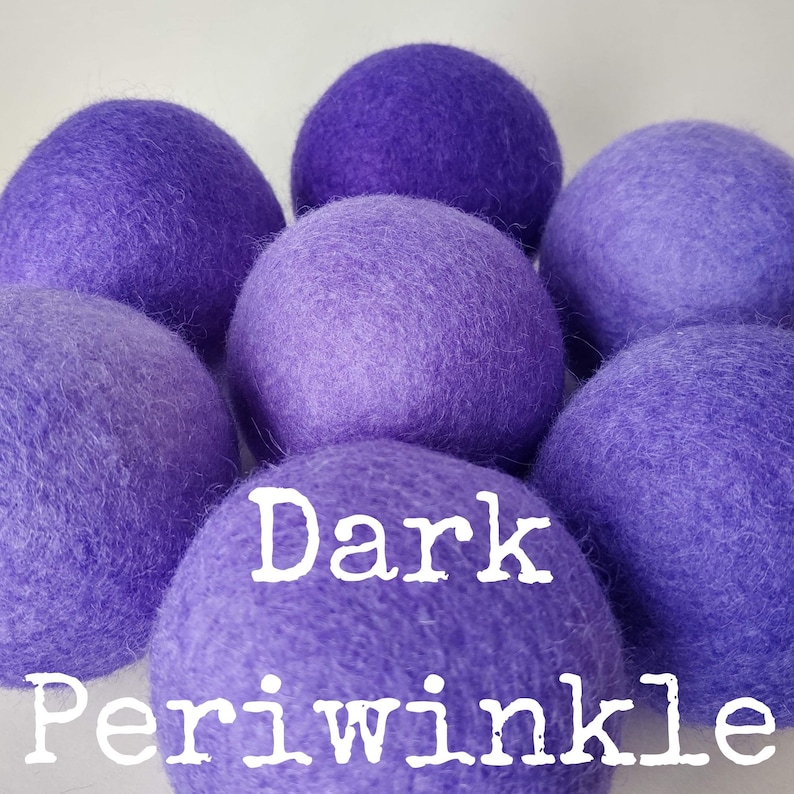 May include: A group of seven dark periwinkle wool dryer balls. The balls are soft and fluffy, and they are a natural way to soften laundry and reduce static.