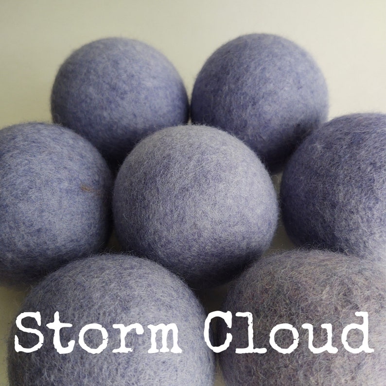 May include: Six lavender-colored wool dryer balls, arranged in a circle, with the text "Storm Cloud" in white letters at the bottom of the image.