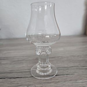 Peut inclure: Une tasse en céramique blanche avec une anse noire et le texte "But First, Coffee" en gras noir. La tasse est posée sur un fond flou, soulignant son design épuré.