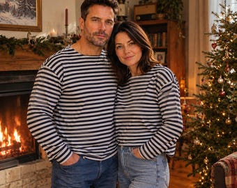 May include: Two long-sleeve shirts featuring a horizontal navy blue and white striped pattern with a crew neckline. The shirts are made of a lightweight fabric and are worn with blue denim jeans, creating a coordinated look for the holiday season.