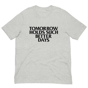 May include: A light gray t-shirt with the text "TOMORROW HOLDS SUCH BETTER DAYS" in bold black letters. The shirt is a short-sleeved crew neck style, suitable for casual wear.