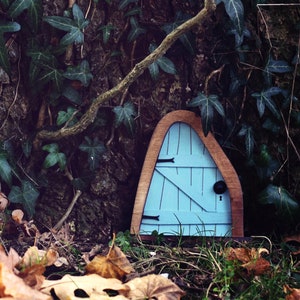 a blue fairy door in front of a tree