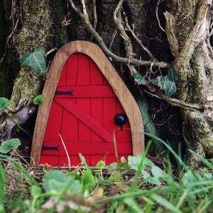 a small red fairy door in the middle of the forest