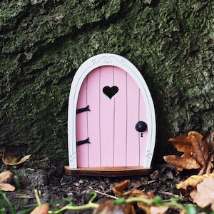 a small pink fairy door with a heart shaped window