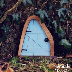 a small blue fairy door in the middle of the forest