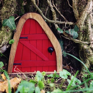 a small red fairy door in the middle of the forest