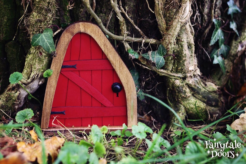 a small red fairy door in the middle of the forest