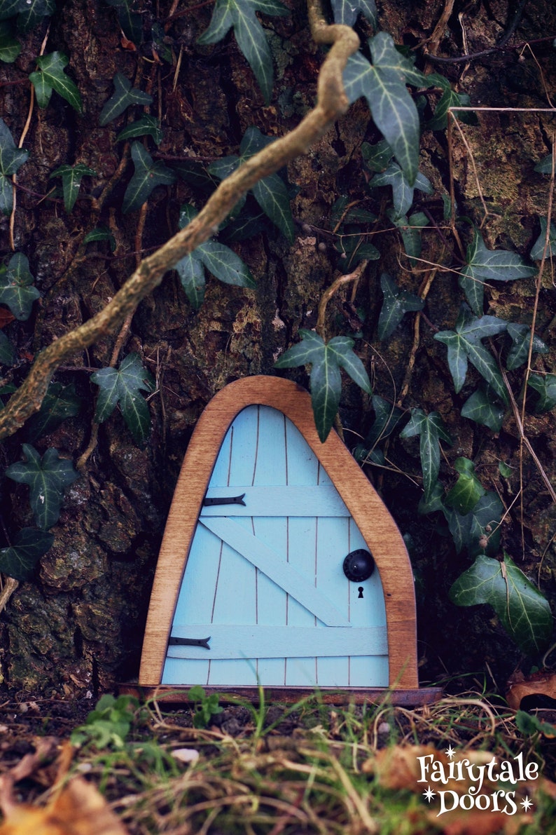 a small blue fairy door in the middle of the forest