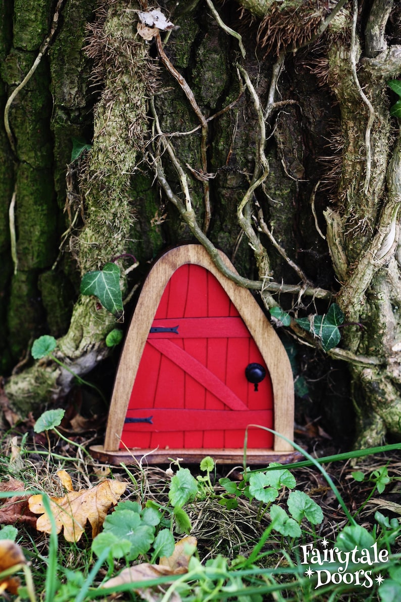 a small red fairy door in front of a tree