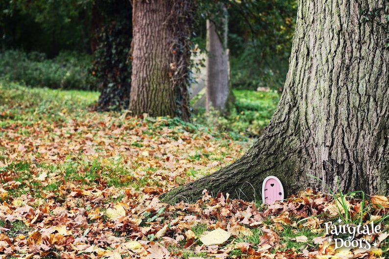 a pink fairy door in front o fa tree