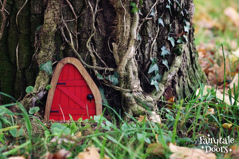 a small red fairy door in the middle of the forest