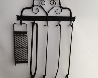 Rejilla de cocina antigua de hierro forjado con espátula, tenedores, gofrera y rallador. Década de 1900 Rejilla antigua de hierro forjado con utensilios de cocina | Decoración de cocina de granja