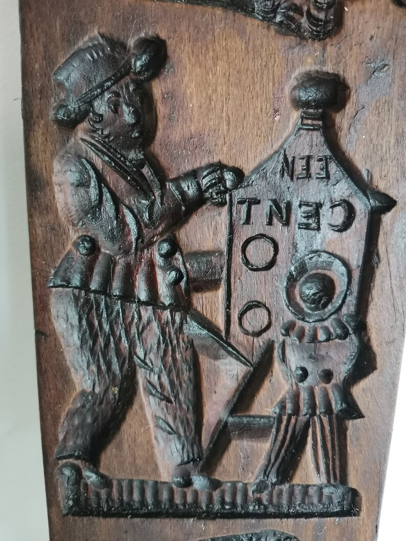 May include: A wooden cookie mould with a carved design of a person holding a sign that says "One Cent".