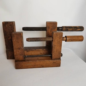 May include: Two wooden clamps with metal screws and wooden handles. The clamps are made of dark brown wood and are in a used condition.