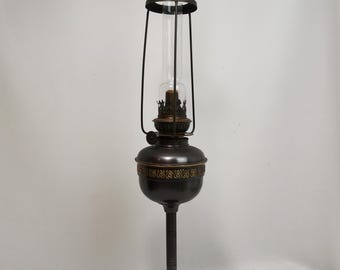 Lampe à huile ancienne en métal anthracite avec éléments dorés et cuivrés et cheminée en verre, modèle Kosmos Brenner des années 1900 | Lampe à huile de table