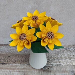 Five yellow origami paper sunflowers in a white vase