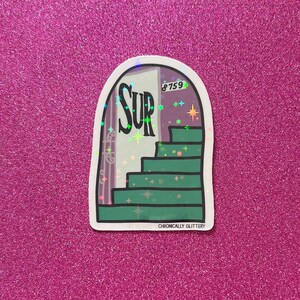 May include: A sticker with a holographic finish depicting a green staircase leading up to a door with the word "SUR" on it. The door has a purple background with a white number "8759" above the word "SUR". The sticker has a white border and the text "CHRONICALLY GLITTERY" at the bottom.