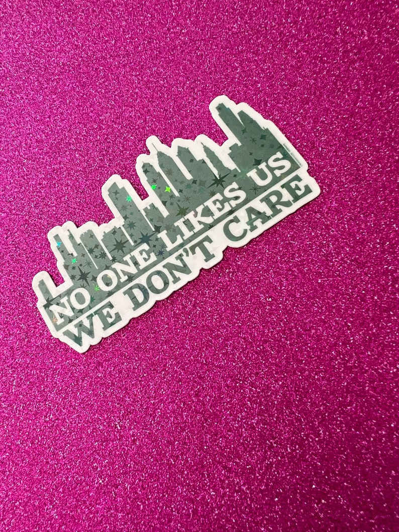 May include: A white sticker with a black silhouette of a city skyline and the text "NO ONE LIKES US WE DON'T CARE" in black.