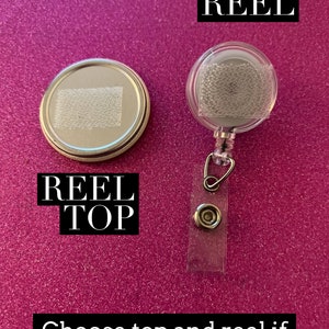 May include: Two silver badge reels, one with a clear plastic cover and the other with a silver top. The reel with the clear plastic cover has the word "REEL" printed on it. The reel with the silver top has the words "REEL TOP" printed on it. Choose top and reel if you need both!