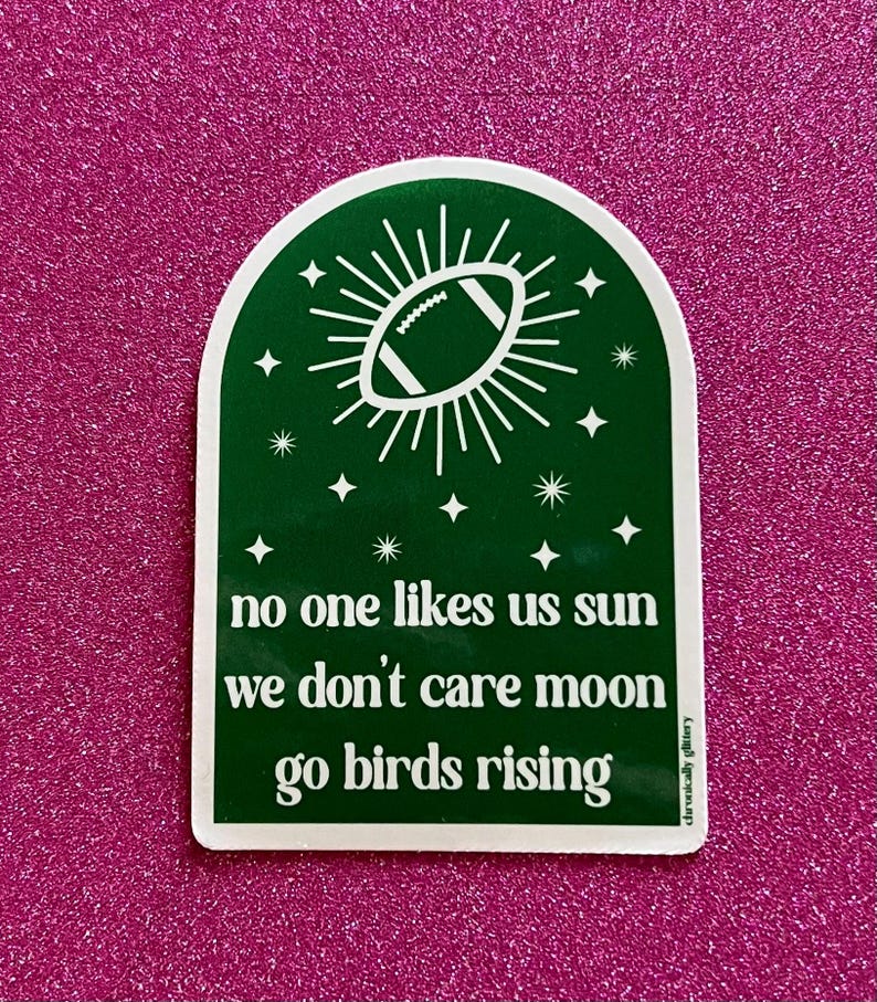 May include: Green sticker with a white football inside a sunburst design. The text reads "no one likes us sun we don't care moon go birds rising".