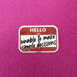 May include: A red and white sticker with the text "HELLO I am unable to make simple decisions".